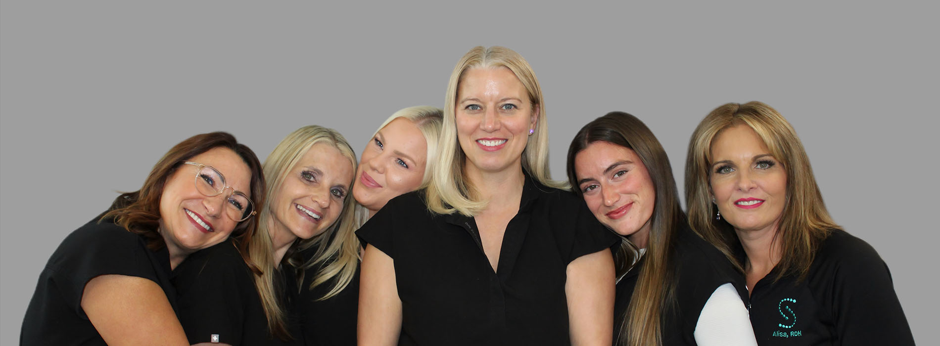 The image is a photograph of a woman with light skin, smiling at the camera. She appears to be in her late twenties or early thirties and has long hair. Her eyes are looking directly at the camera, and she is holding up her index finger near her mouth as if she s making a point or emphasizing something. The background is plain and light-colored, which suggests that this could be a stock photo used for various purposes such as advertising, personal branding, or lifestyle content.