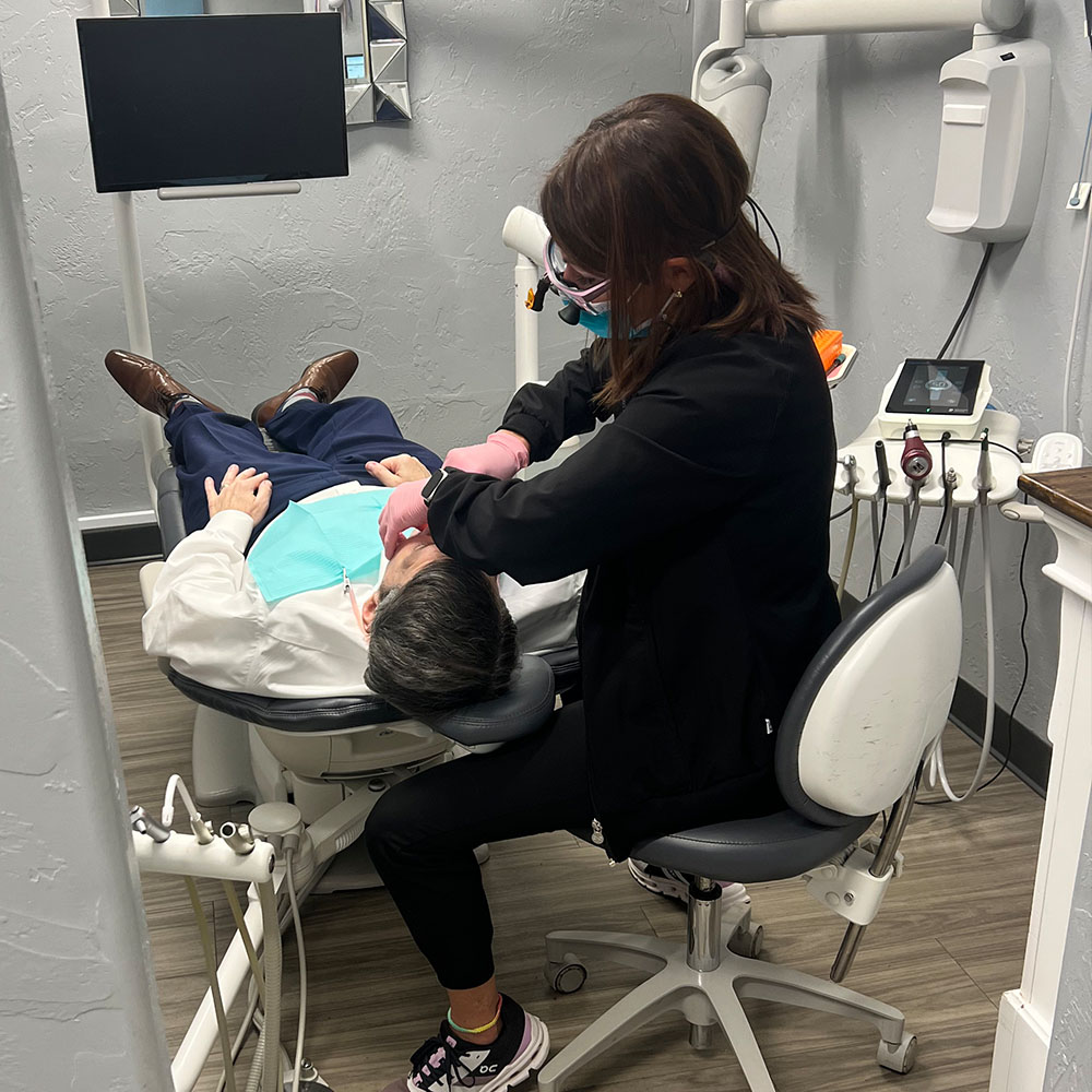 A dental professional performing a dental procedure on a patient in a dental office.